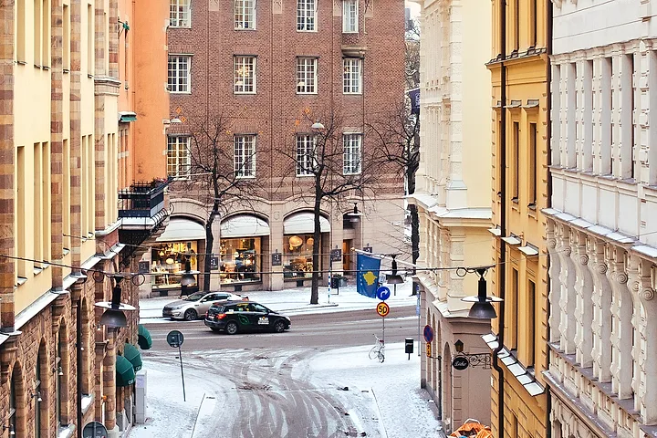 Snötäckt gata i Stockholms innerstad med hjulspår och en korsande bil