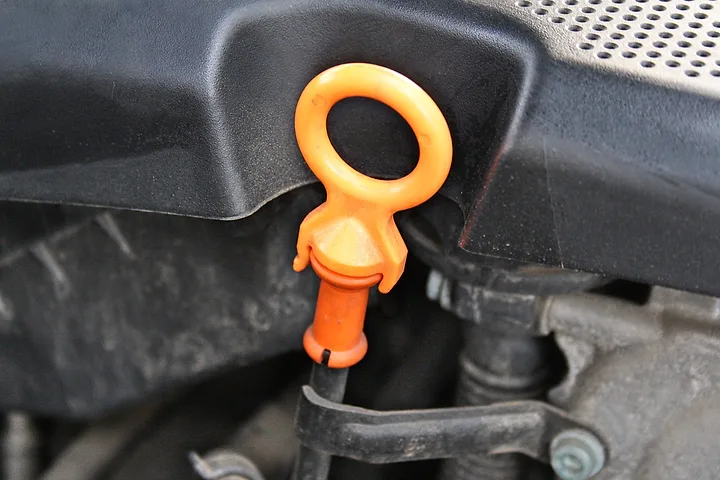 Orange handtag på mätstickan för motorolja i ett motorrum