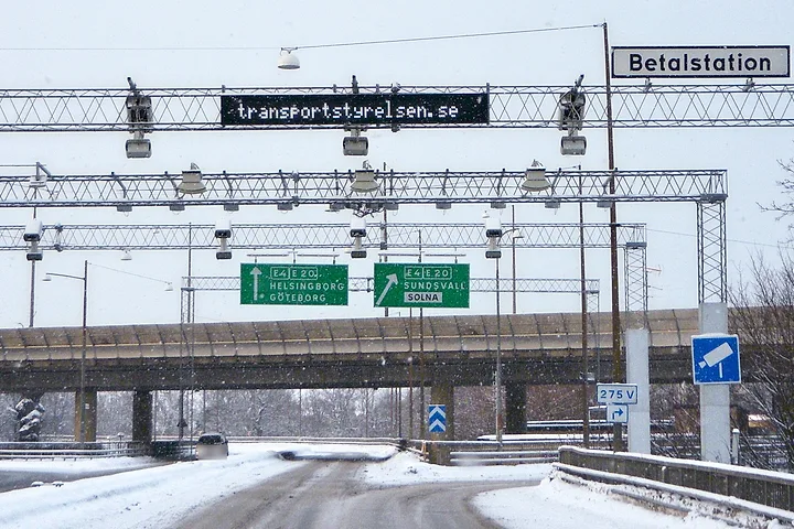 Betalstation för trängselskatt med kameror på portaler över en snöig väg, under skylten Betalstation