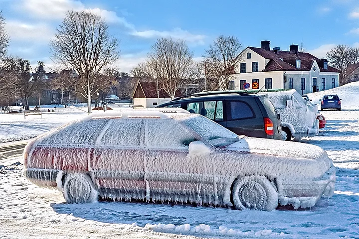 Bil helt täckt av is på en snöig parkering i Visby