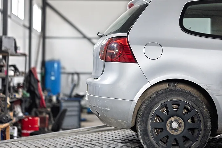 Silverfärgad bil på flaket till en bärgningsbil inne i ett garage
